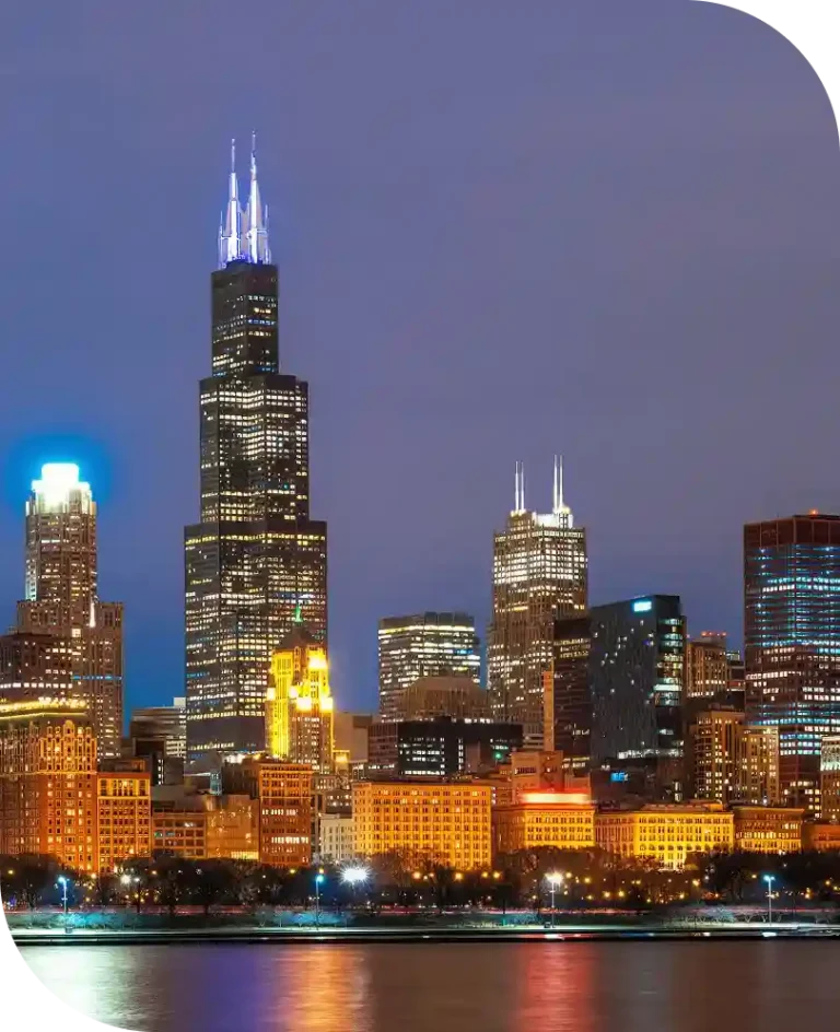 Night view of Chicago's skyline, featuring the Willis Tower and other illuminated skyscrapers.