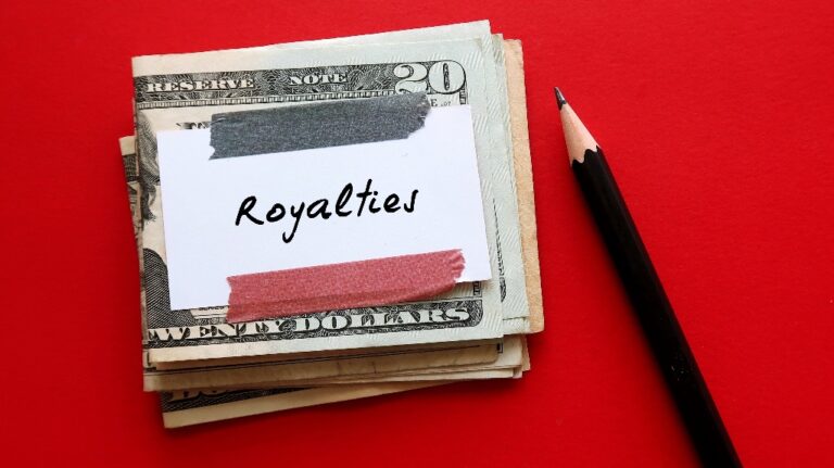 Cash money dollar and pencil on red background with note written ROYALTIES